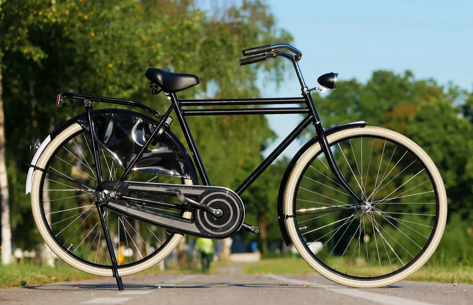 A black city bicycle with cream tyres on a path