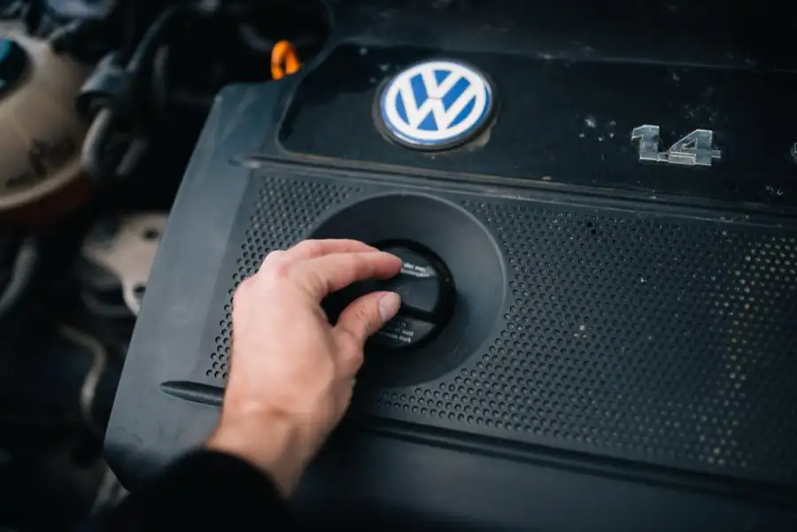 A hand unscrewing the oil filler cap on an engine cover