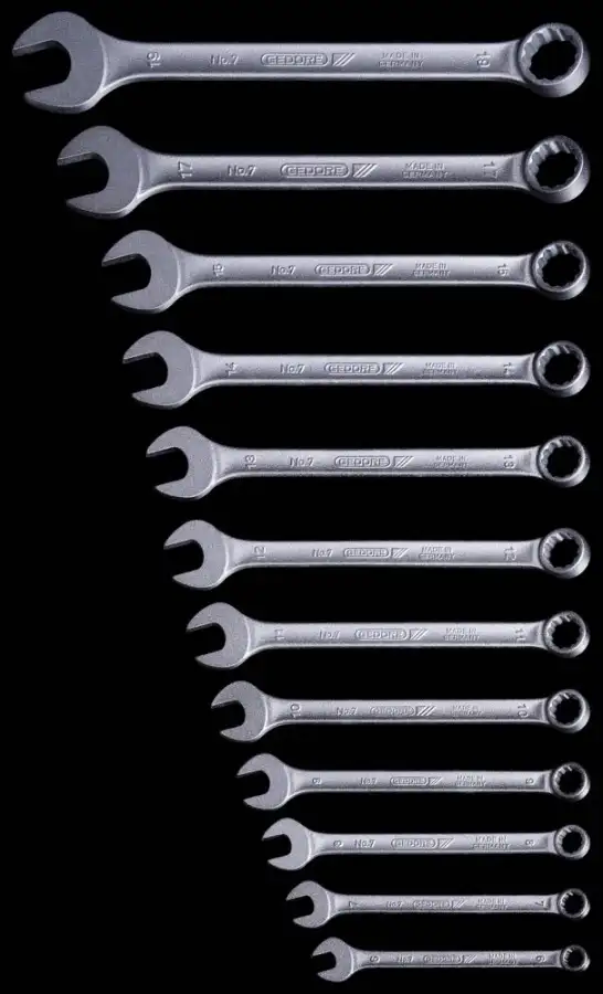 A row of combination wrenches from small to large on a black background