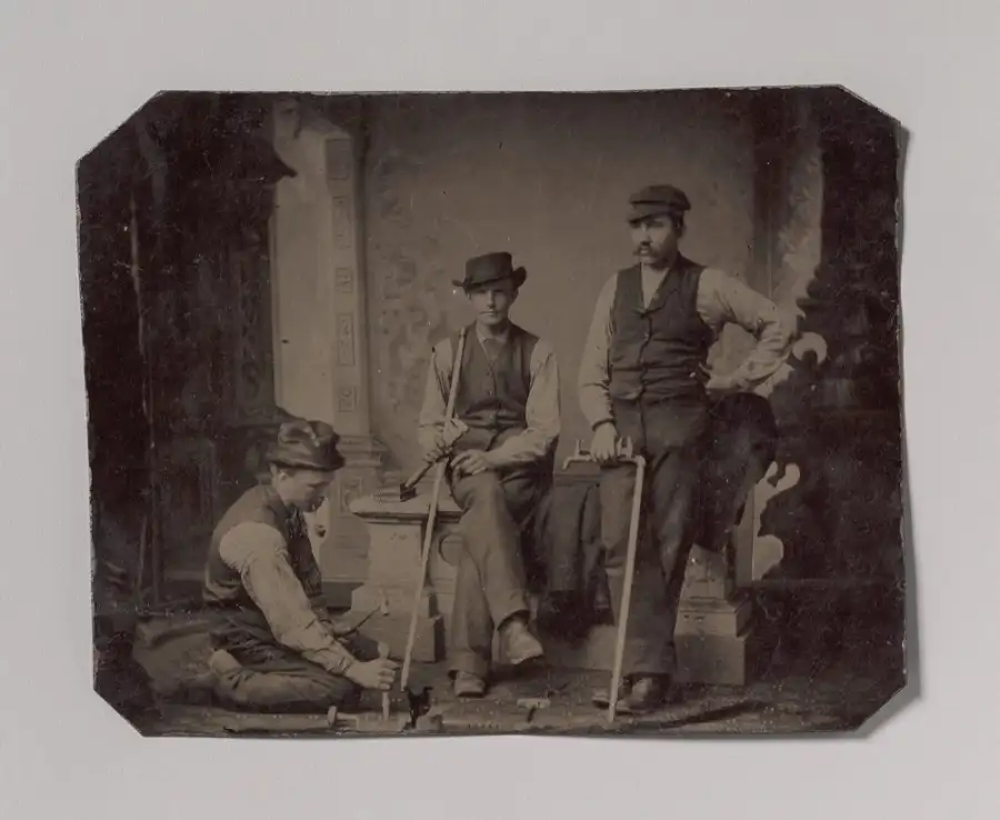 A nineteenth-century tintype portrait of three plumbers holding pipes and tools