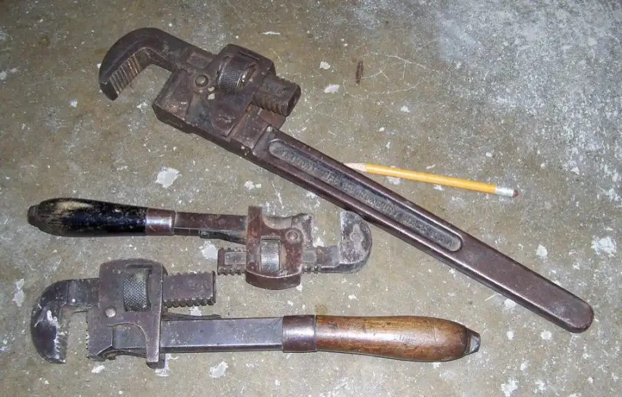 Two old pipe wrenches lying on a concrete floor